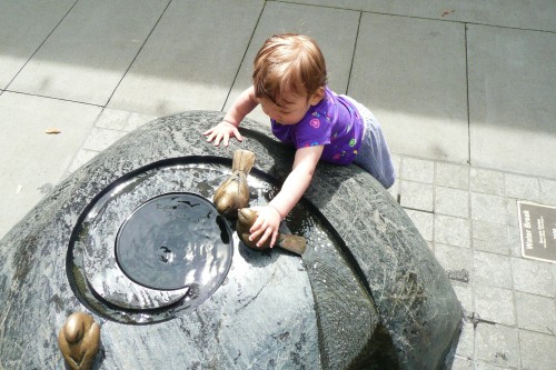An adorable toddler plays in a water feature