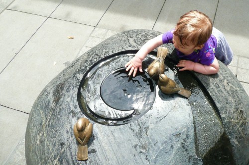 An adorable toddler plays in a water feature